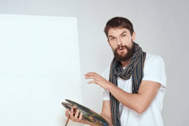 Sanatçı paleti ve boynundaki eşarp bir sanat sehpasının ellerinde hafif bir arkaplan.