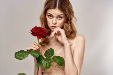 Elinde gül olan kızıl saçlı bir kadın açık arkaplanda duygu modeli portresi.