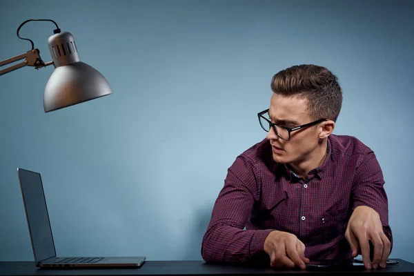 Um homem em uma camisa com um laptop na mesa é um gerente no escritório e um modelo de armário de lâmpadas — Fotografia de Stock