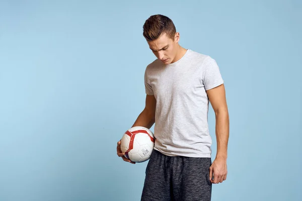 Cara feliz com bola de futebol na mão no fundo azul joga futebol vista cortada — Fotografia de Stock