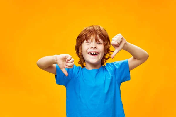 Joyful roodharige jongen met open mond tonen duimen naar beneden blauwe t-shirt — Stockfoto