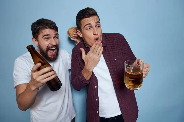 Dos alegres amigos borrachos bebiendo cerveza estilo de vida emociones sobre un fondo azul — Foto de Stock