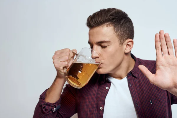 Fylld man med en mugg öl semester alkohol livsstil i en röd skjorta känslor ljus bakgrund — Stockfoto