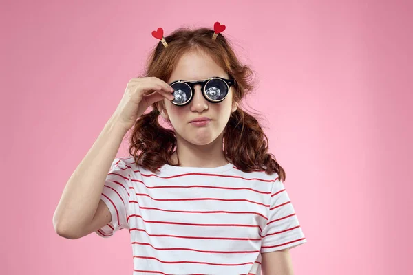 Vrolijk meisje met pigtails zonnebril gestreept t-shirt lifestyle roze achtergrond — Stockfoto