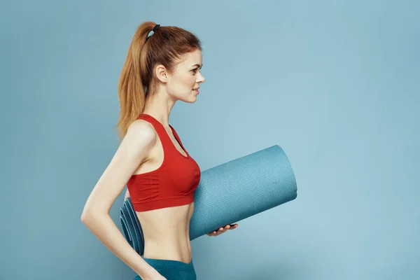 Esterilla de entrenamiento de mujer deportiva en las manos Red Tank Top ejercicio fondo azul — Foto de Stock