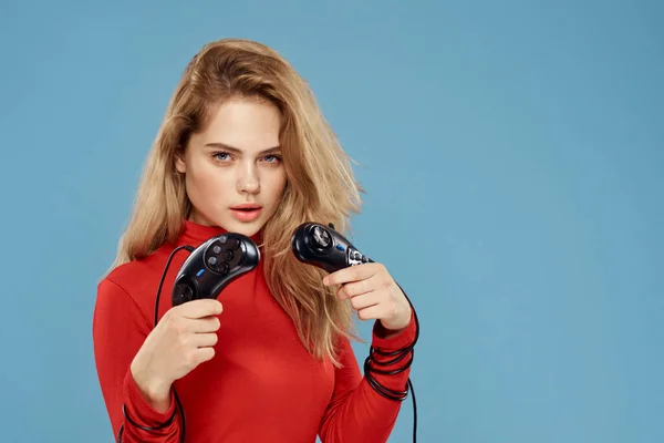 Mujer sosteniendo en sus manos dos controladores de juego entretenimiento estilo de vida chaqueta roja fondo azul — Foto de Stock