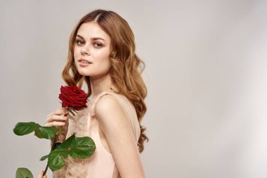 Elinde gül olan kızıl saçlı bir kadın açık arkaplanda duygu modeli portresi.