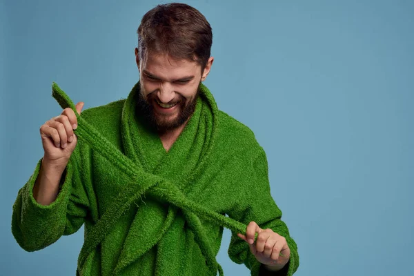 Homem barbudo em roupão verde com cinto em fundo azul vista cortada da emoção — Fotografia de Stock