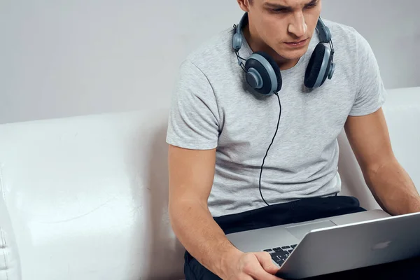 Mężczyzna na kanapie przed laptopem z joystickiem w słuchawkach technologii gier wideo — Zdjęcie stockowe