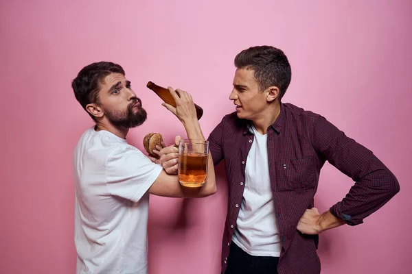 两个男人喝啤酒、友谊、酗酒、生活方式、粉色背景 — 图库照片