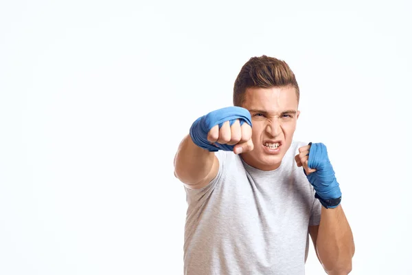 Boxeador masculino deportivo con guantes azules practicando golpes sobre un fondo claro recortado vista — Foto de Stock