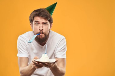 Pastalı sakallı ve şapkalı bir adam doğum gününü kutluyor.