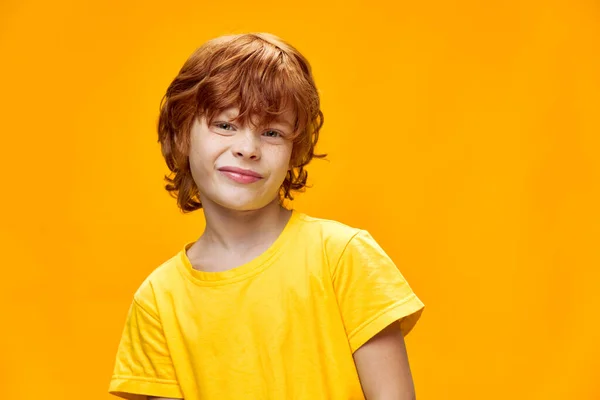 Portrait of a red-haired boy who has curled his face against — Stock Photo, Image