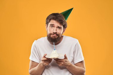 Pastalı sakallı ve şapkalı bir adam doğum gününü kutluyor.