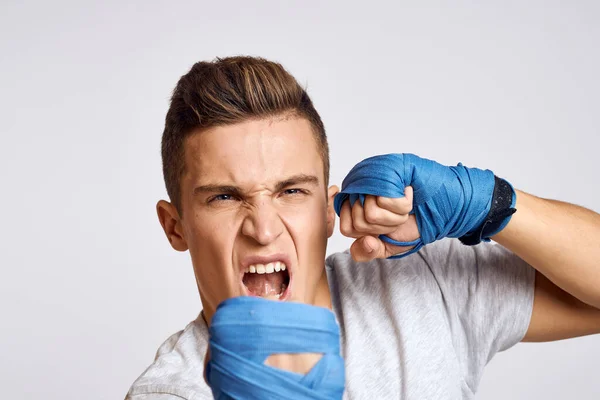 Boxeador masculino deportivo con guantes azules practicando golpes sobre un fondo claro recortado vista — Foto de Stock