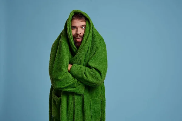 Seorang pria dengan kepala bersembunyi di jubah hijau pada latar belakang biru dipotong tampilan Copy Space — Stok Foto