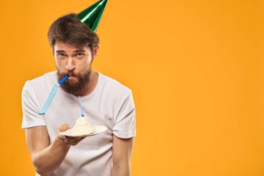 Pastalı sakallı ve şapkalı bir adam doğum gününü kutluyor.