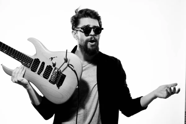 Een man met een gitaar emoties muziek spel prestaties lederen jas zonnebril licht achtergrond — Stockfoto