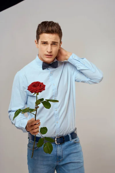 Portret van een knappe man met een rode roos en in een licht hemd geknipt uitzicht — Stockfoto