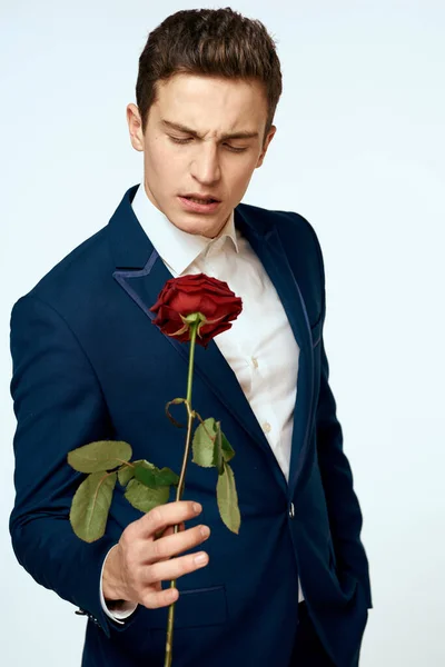 Ein Mann im Anzug mit einer Rose in der Hand ein Geschenk Datum Licht Hintergrund — Stockfoto