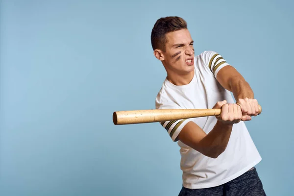 Ragazzo del baseball con un pipistrello in mano su uno sfondo blu e un colore di combattimento sulla sua t-shirt modello trucco viso — Foto Stock