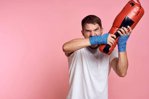 Hombre practicando golpes en una pera boxeo vendajes fitness estilo de vida rosa fondo — Foto de Stock