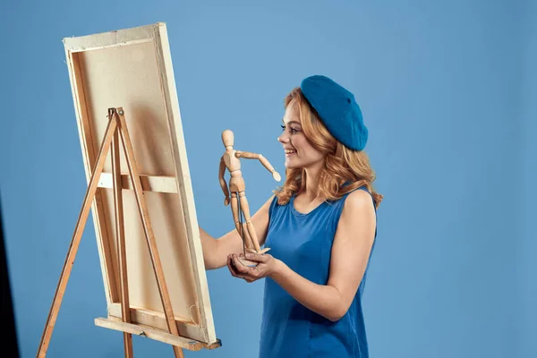 Mulher artista segurando manequim de madeira cavalete arte em mãos Criativa passatempo azul fundo — Fotografia de Stock