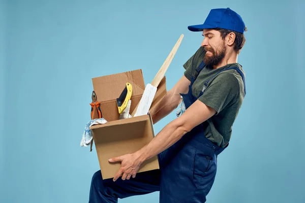 유니폼 상자 도구를 가지고 파란색 배경을 만들고 있는 노동자 — 스톡 사진