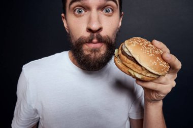Hamburger yiyen fast food restoranı gurmesi karanlık arka plan yiyor.