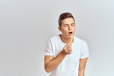 Patates kızartması tutan duygusal bir adam fast food hafif arka plan beyaz tişört kırpılmış manzara