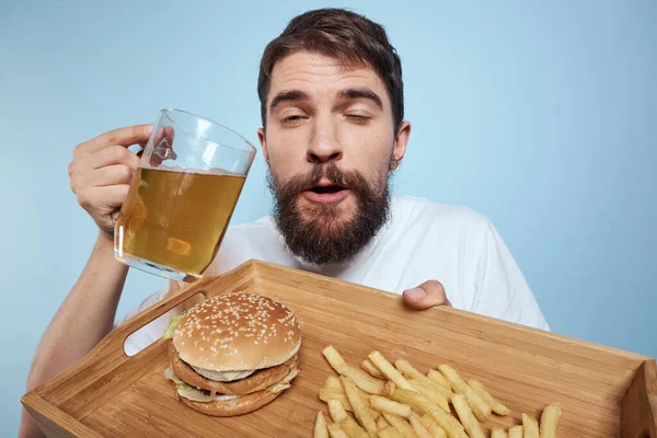 Gai homme bière tasse hamburger frites fast food régime bleu fond close-up — Photo