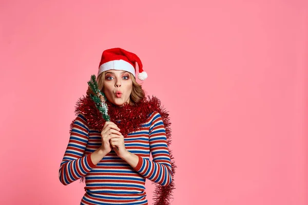 Žena s vánoční strom větve v rukou červená tinsel a slavnostní klobouk růžové pozadí oříznutý pohled — Stock fotografie