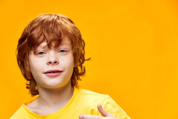 Κόκκινο αγόρι μαλλιά σε ένα απομονωμένο φόντο σε ένα κίτρινο t-shirt — Φωτογραφία Αρχείου