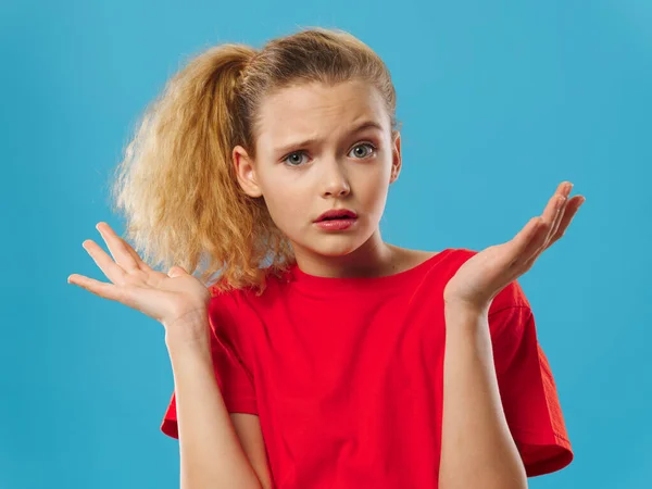 Menina surpresa em um vermelho gestos camiseta com as mãos — Fotografia de Stock