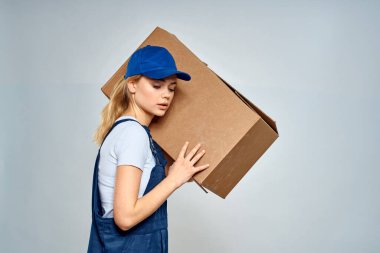 Teslimat servisi arkaplanındaki kutuda çalışan üniformalı bir kadın.