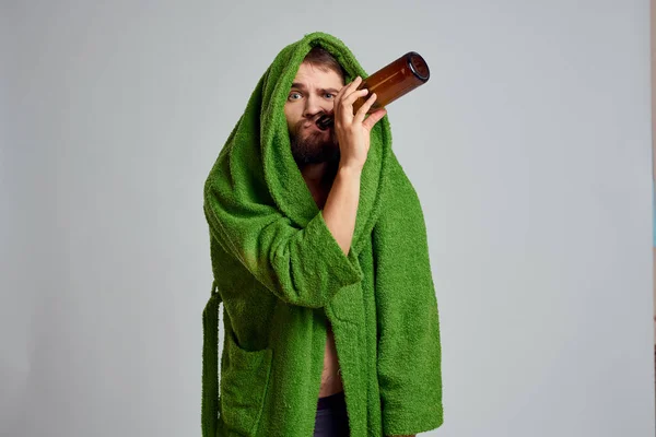 Ubriaco uomo con bottiglia di alcol in mano e vestaglia verde bere relax — Foto Stock