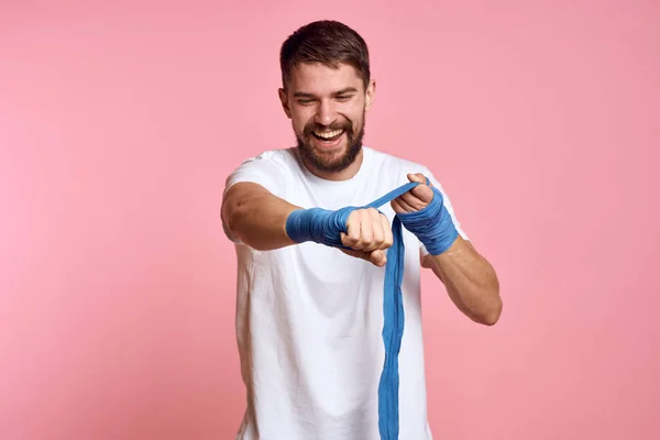 Uomo sportivo in una t-shirt bianca bendaggi boxe sulle mani di uno stile di vita di allenamento sfondo rosa — Foto Stock