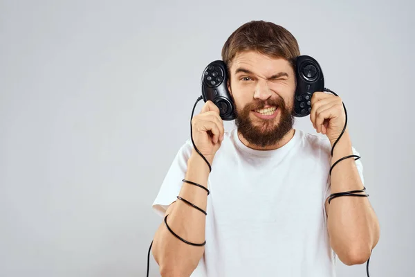 Een man houdt in zijn handen twee joysticks spelen vrijetijdsbesteding technologie levensstijl wit t-shirt — Stockfoto