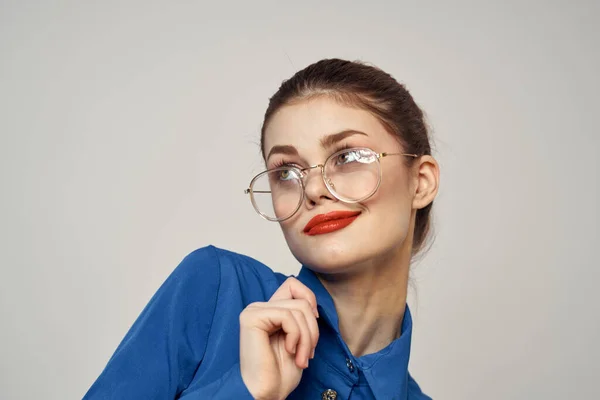 Portrait of emotional woman in blue shirt and glasses bright makeup model light background cropped view Copy Space