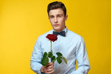 Sarı arka planda kırmızı gül ve açık gömlek papyonlu bir beyefendinin portresi.