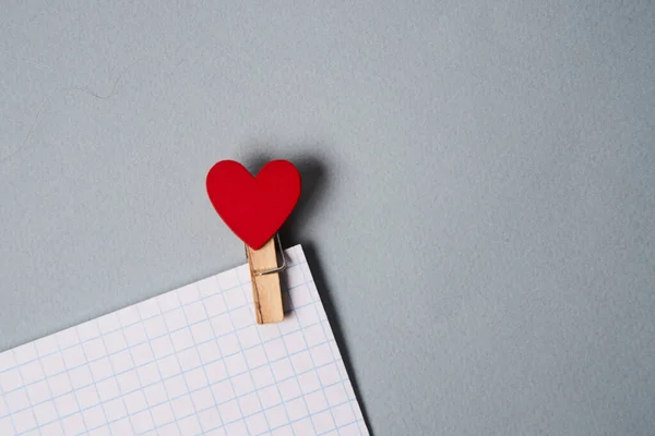 Kolíky v podobě srdíček na bílém listu papíru oříznutý pohled Valentines den dekorace — Stock fotografie