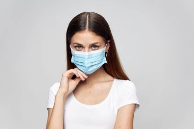 Güzel kadın. Yüzünde tıbbi maske. Önüne bak. Beyaz tişört koruması.