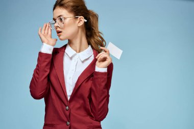 İş kadını kırmızı ceketli, gözlüklü, yönetici mavi arka planlı.