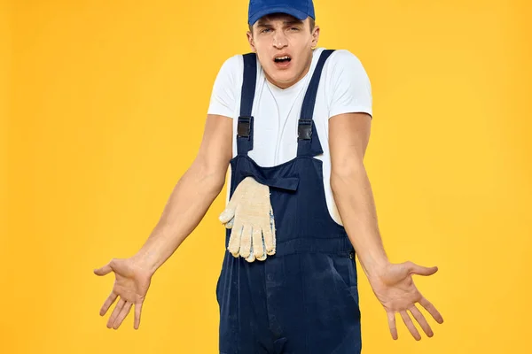 Hombre trabajador en uniforme de guantes prestando servicio fondo amarillo — Foto de Stock