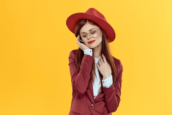 Kvinna i röd hatt jacka glasögon gul bakgrund kosmetika — Stockfoto