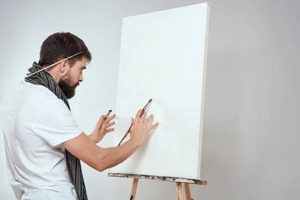Мужчина художник кисть в руках мольберт искусства хобби легкий шарф на заднем плане вокруг его шеи — стоковое фото