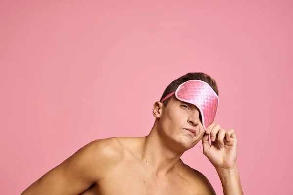 Uomo in maschera rosa sonno su sfondo rosa spalle nude mattina — Foto Stock