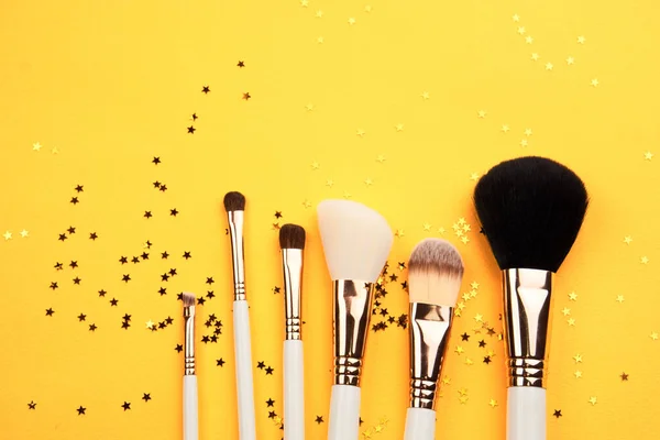 Cepillos de maquillaje en diferentes tamaños sobre un fondo amarillo y aspecto recortado brillo —  Fotos de Stock