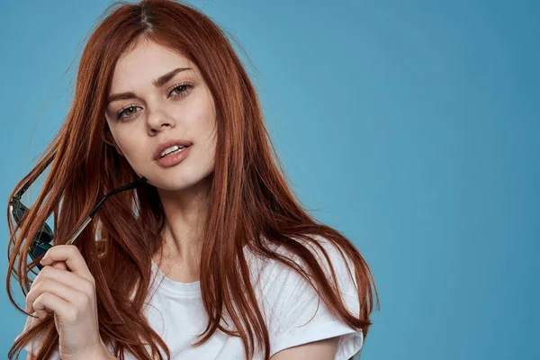 Ellerinde güneş gözlüğü olan güzel bir kadın yaşam tarzı duyguları uzun saç makyaj malzemesi arka planda beyaz tişört.