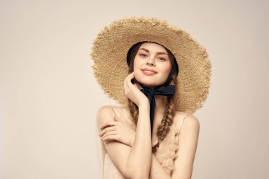 Hasır şapkalı, siyah kurdeleli ve arka planda açık bir elbise giyen hoş bir kız. Romantik bir model.